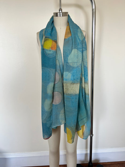 A large chiffon silk scarf with a vibrant, abstract multicolored print, displayed on a mannequin.