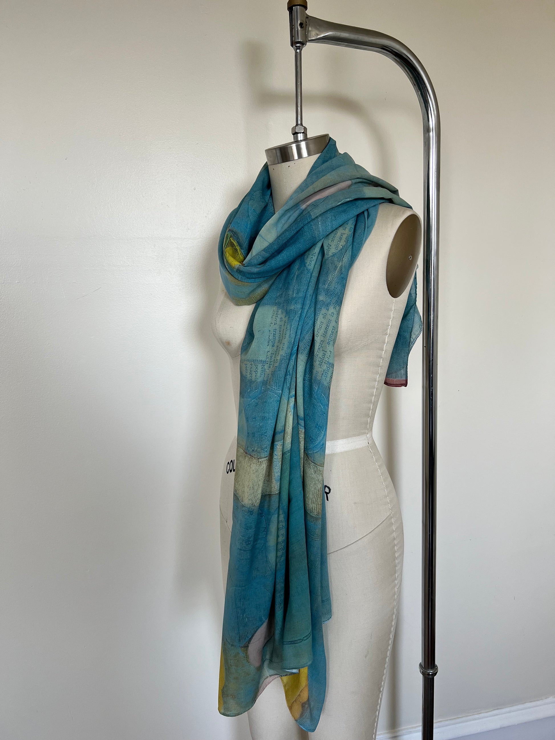 A large chiffon silk scarf with a vibrant, abstract multicolored print, displayed on a mannequin.