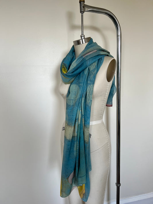 A large chiffon silk scarf with a vibrant, abstract multicolored print, displayed on a mannequin.