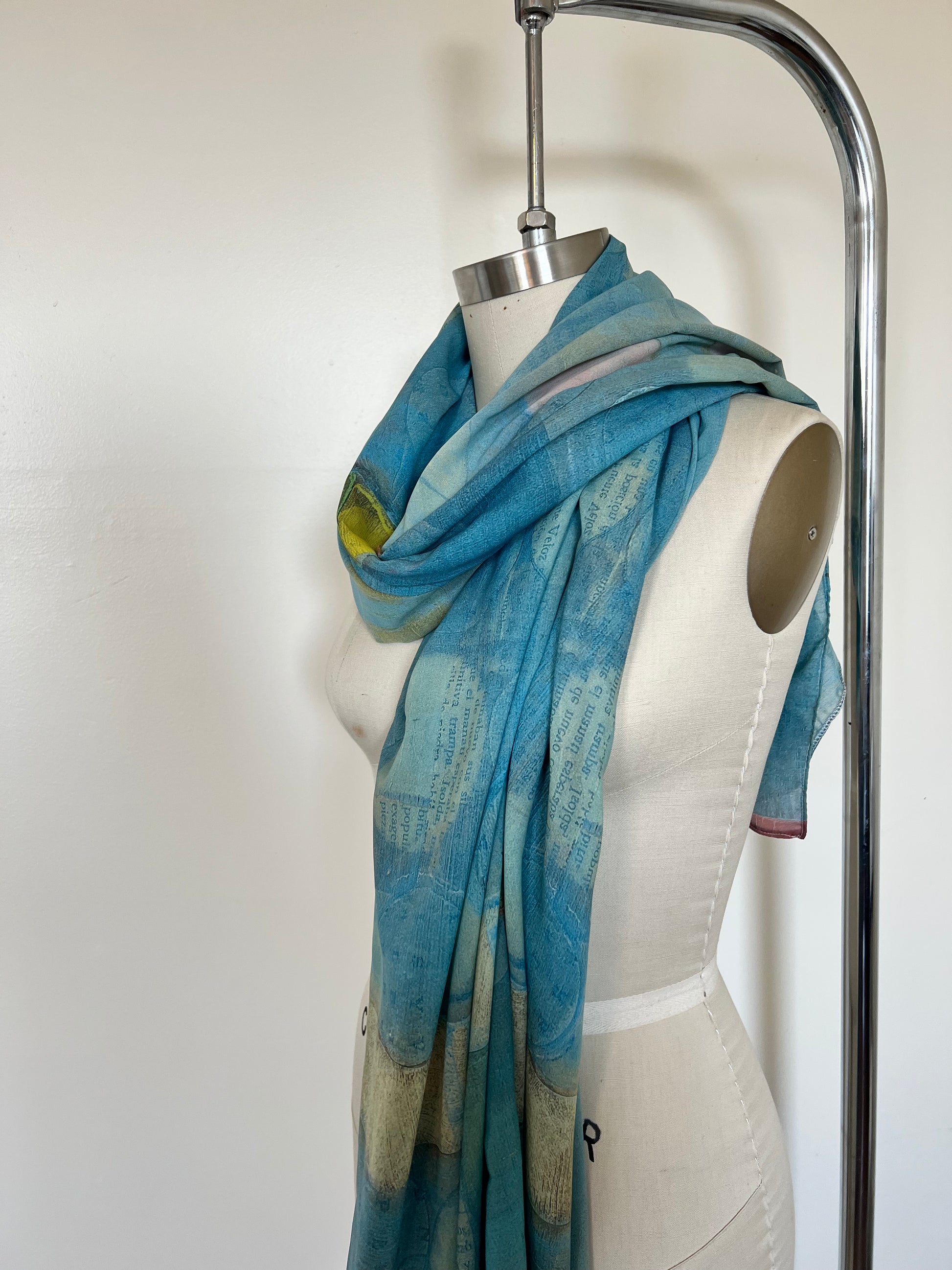 A large chiffon silk scarf with a vibrant, abstract multicolored print, displayed on a mannequin.