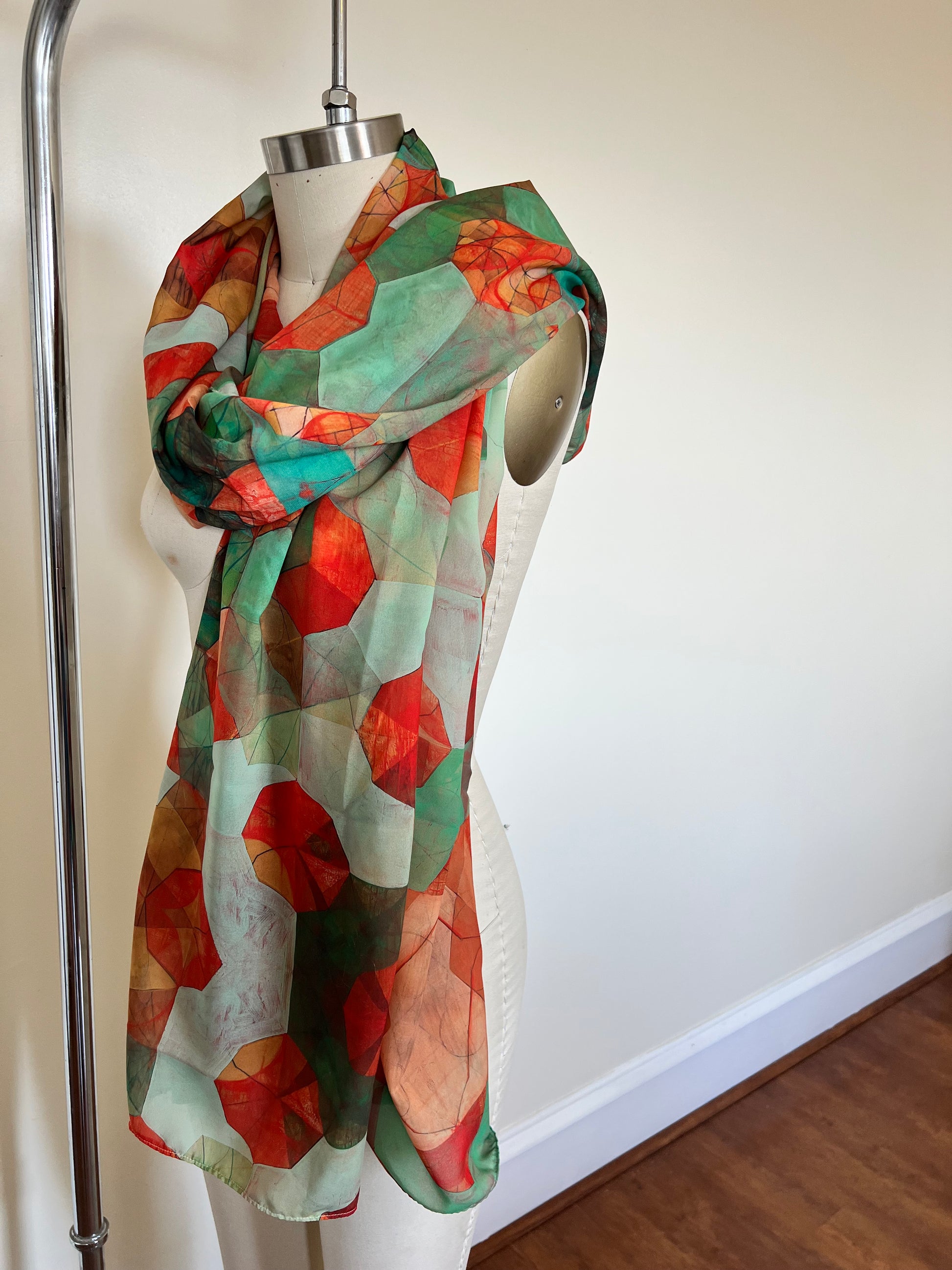 A large chiffon silk scarf with a vibrant, abstract multicolored print, displayed on a mannequin.
