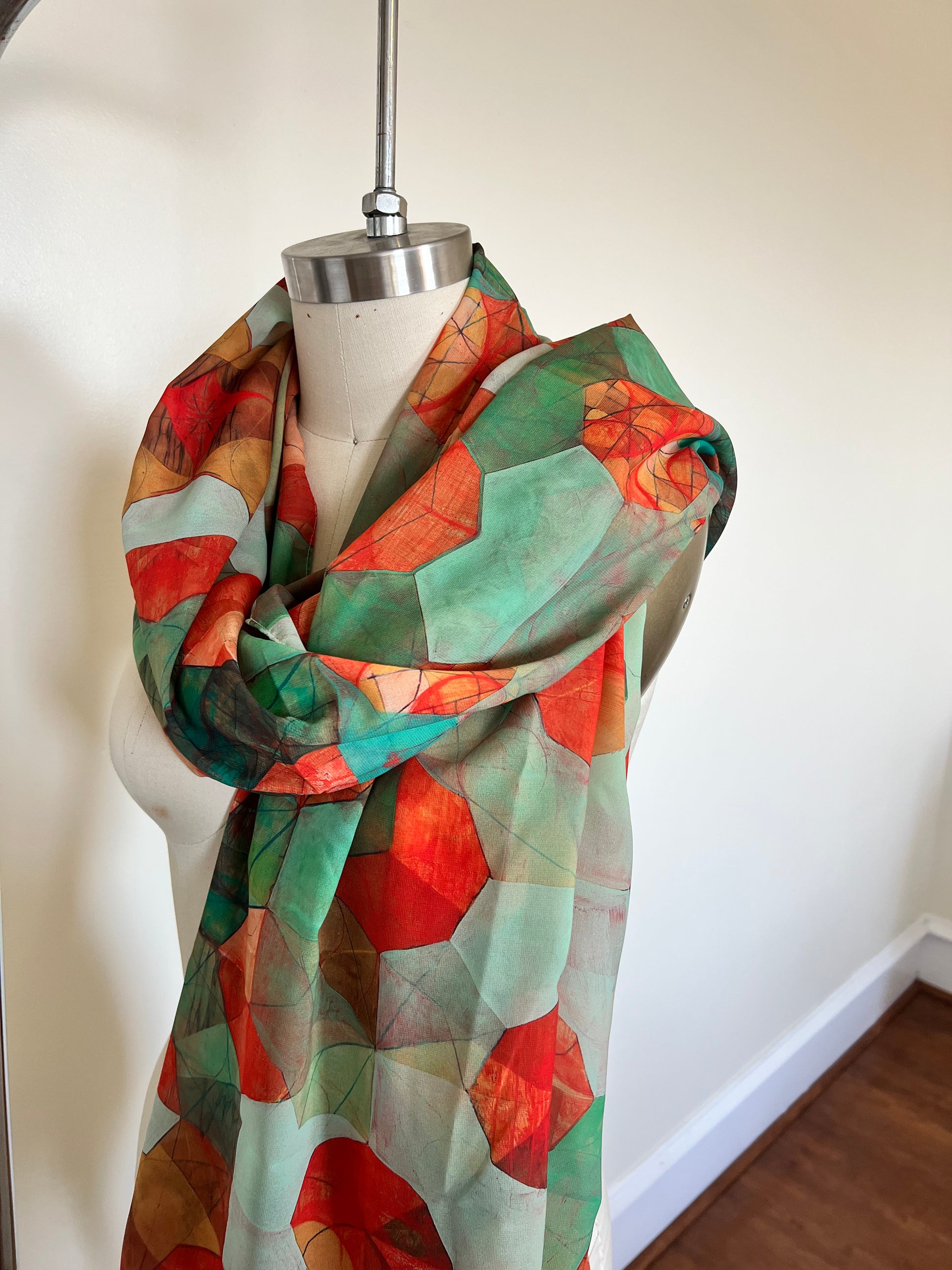A large chiffon silk scarf with a vibrant, abstract multicolored print, displayed on a mannequin.
