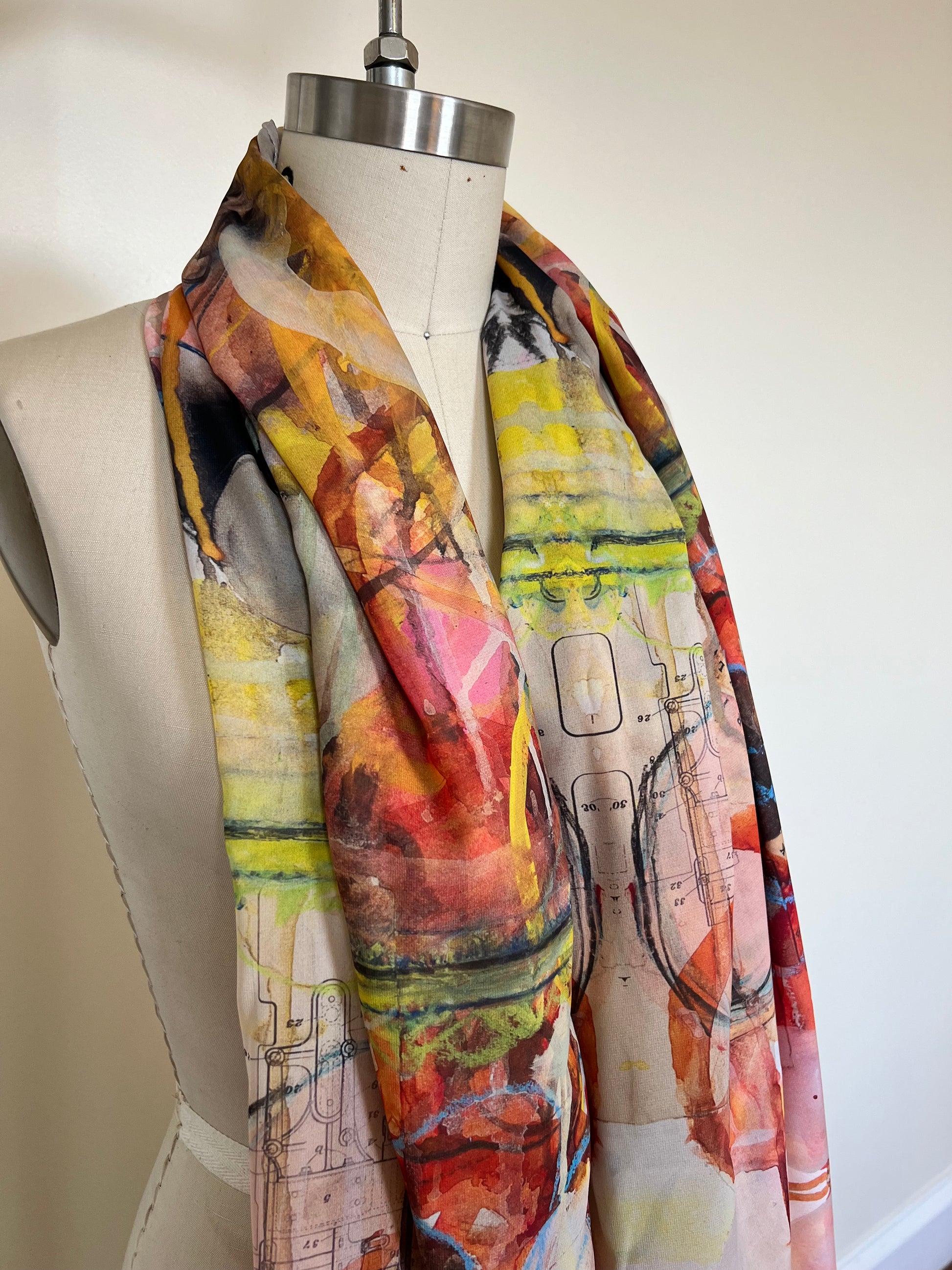 A large chiffon silk scarf with a vibrant, abstract multicolored print, displayed on a mannequin.
