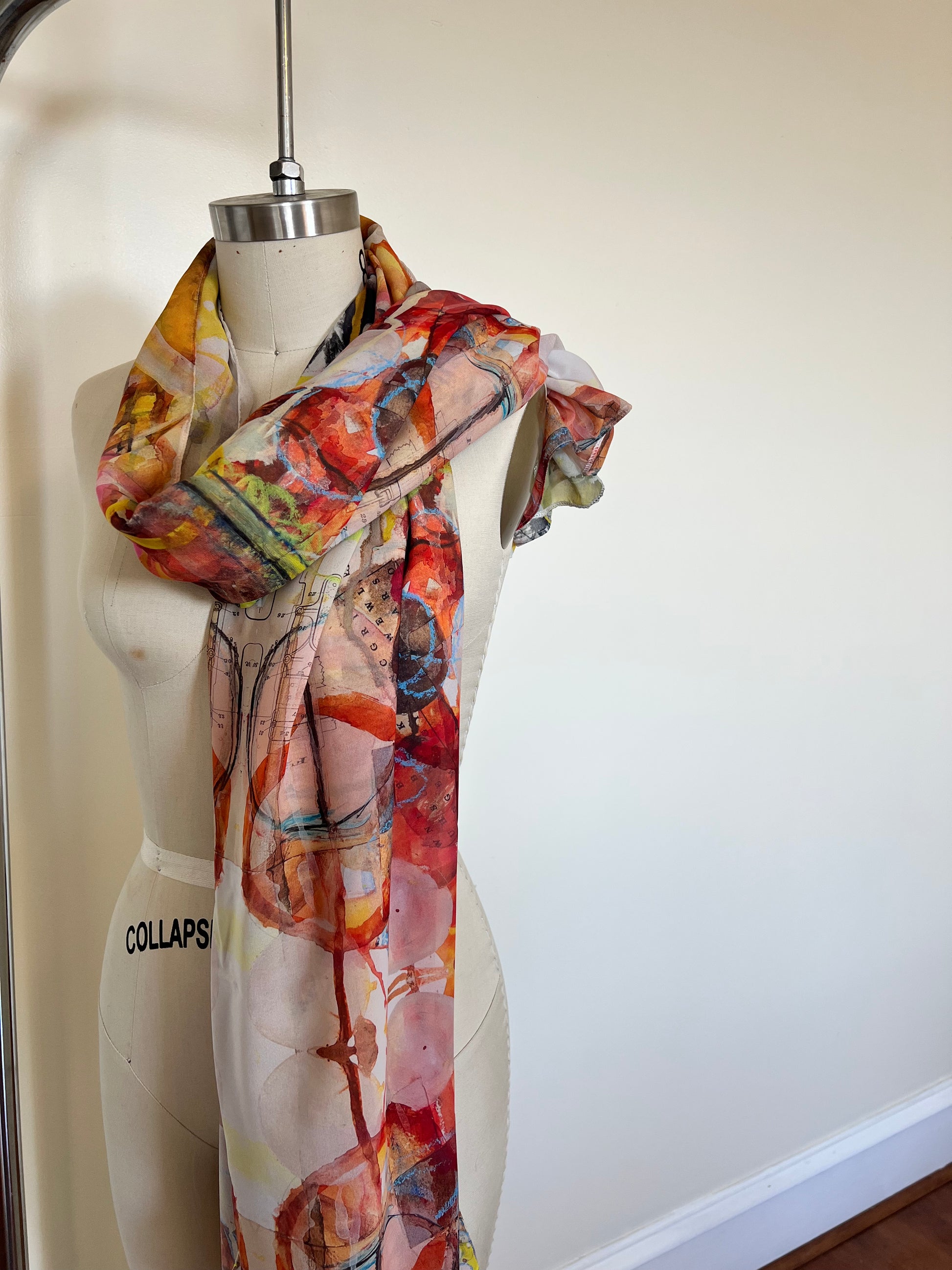 A large chiffon silk scarf with a vibrant, abstract multicolored print, displayed on a mannequin.