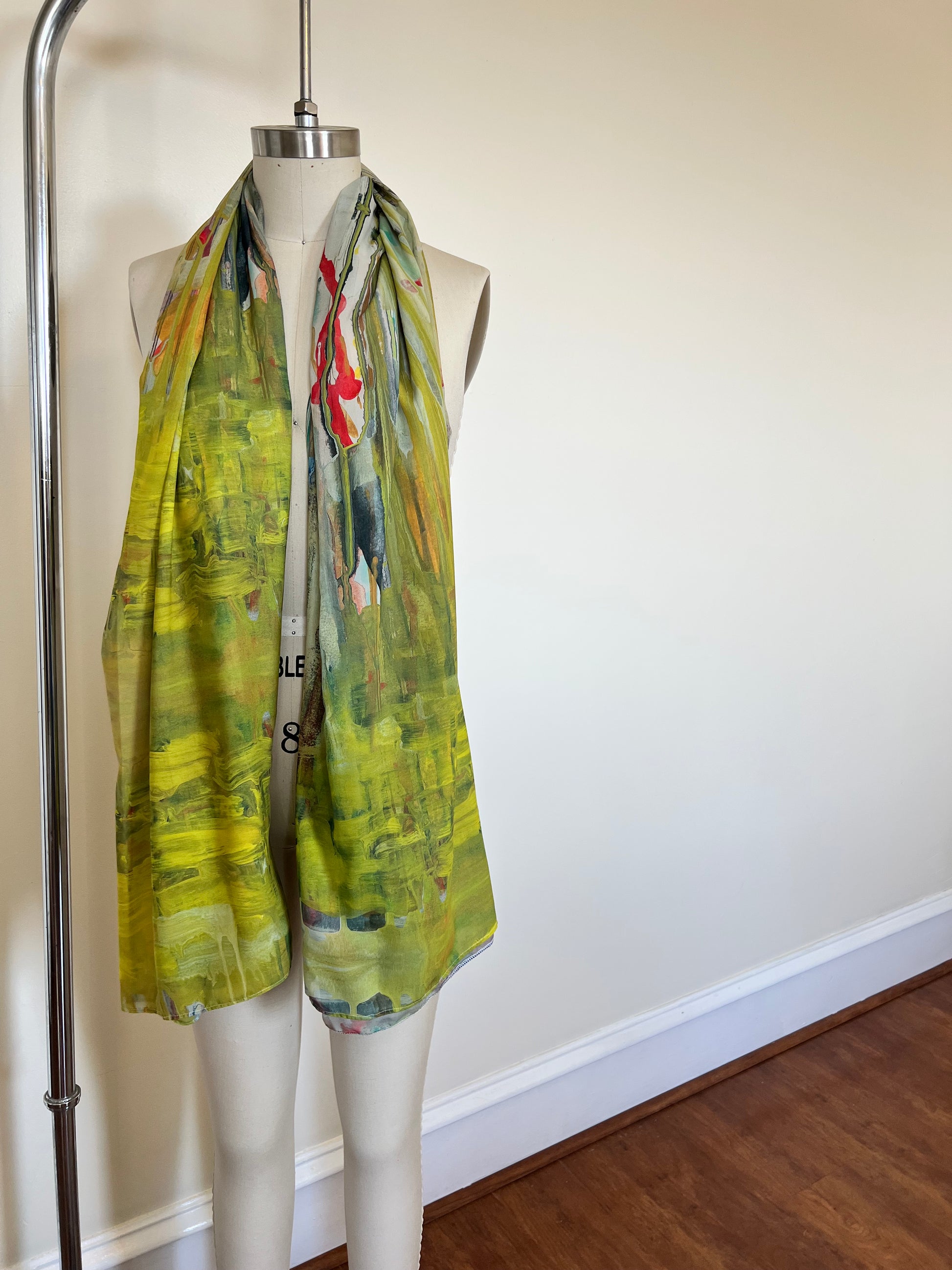 A large chiffon silk scarf with a vibrant, abstract multicolored print, displayed on a mannequin.