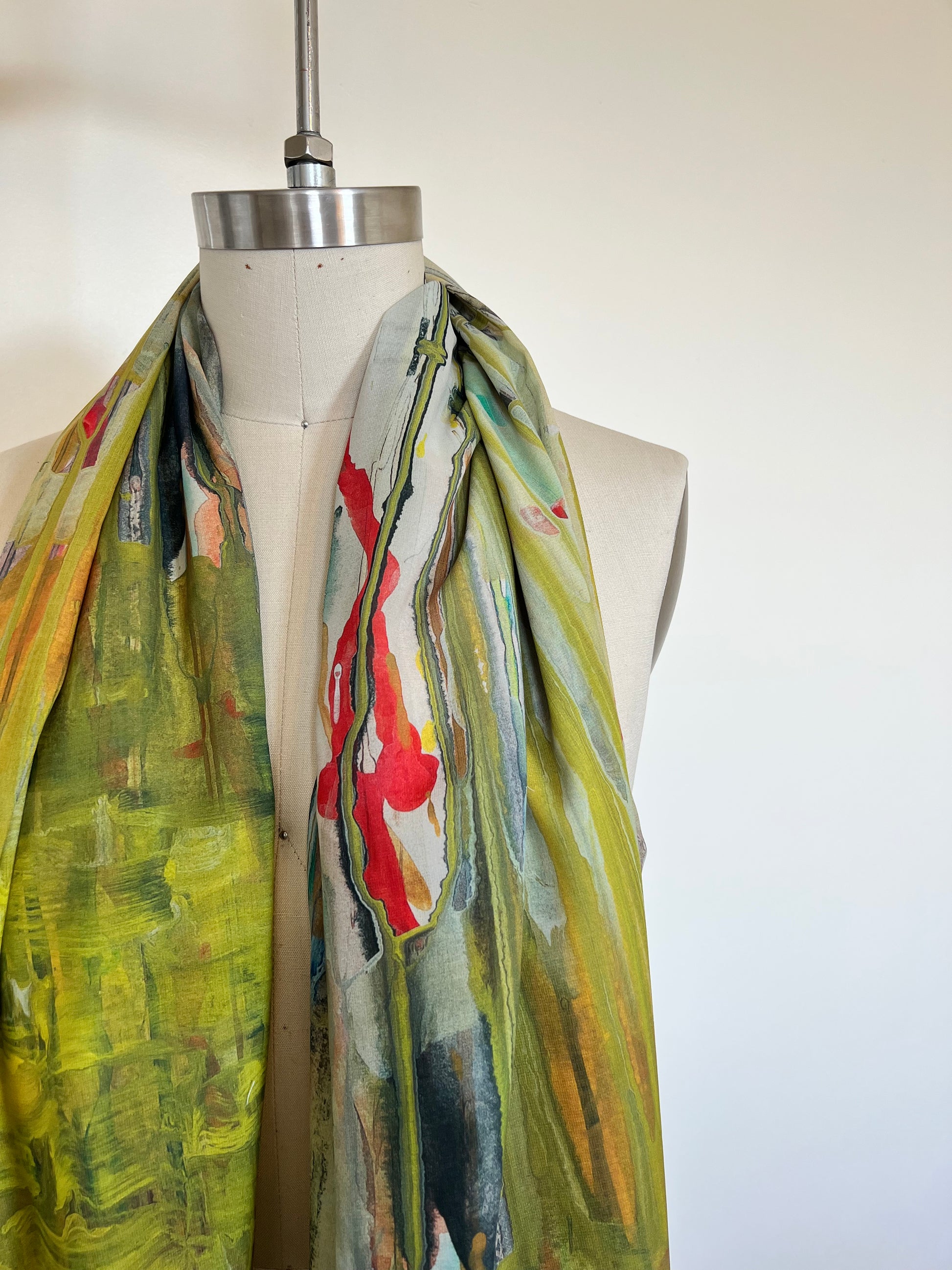A large chiffon silk scarf with a vibrant, abstract multicolored print, displayed on a mannequin.