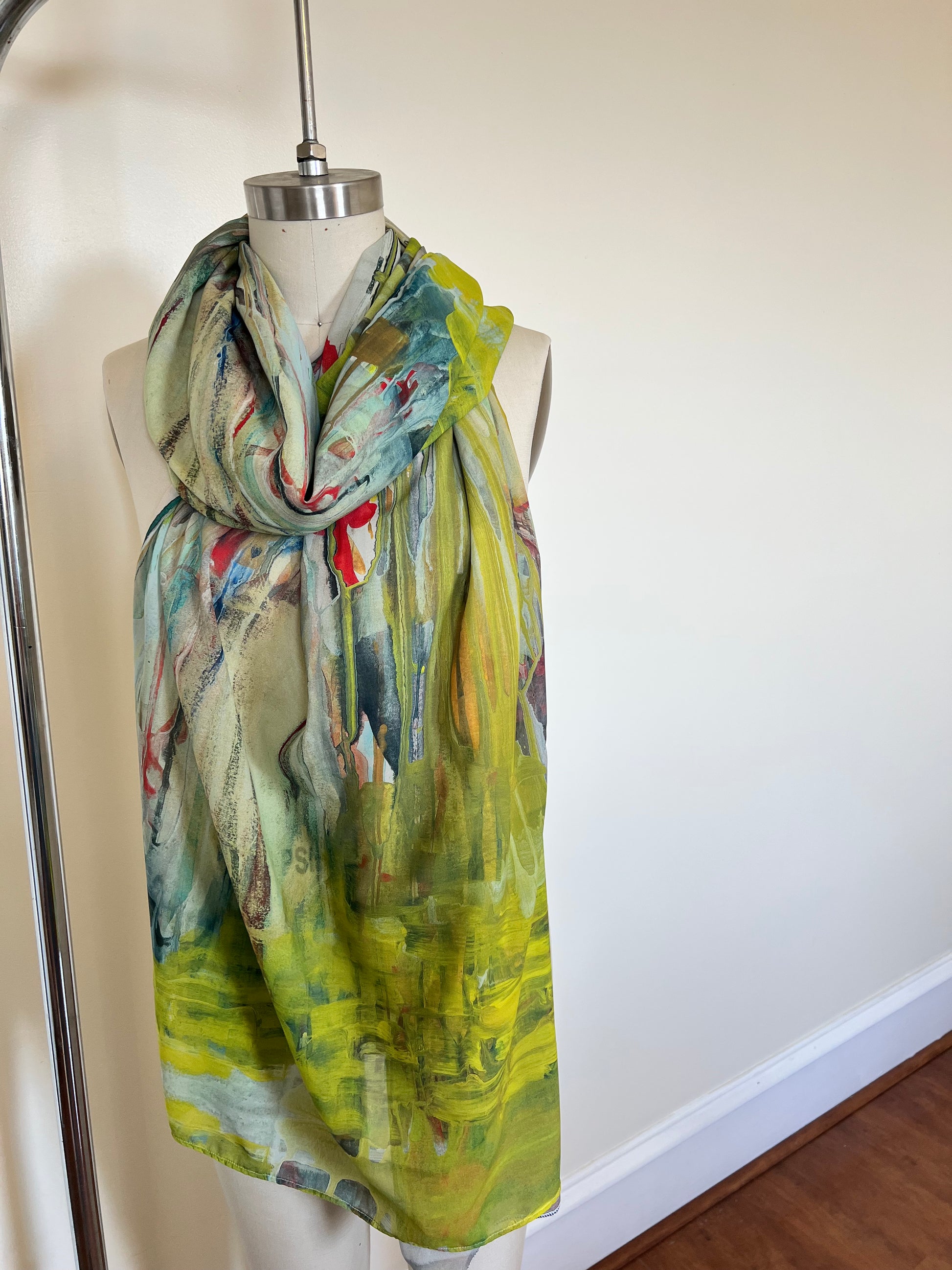 A large chiffon silk scarf with a vibrant, abstract multicolored print, displayed on a mannequin.