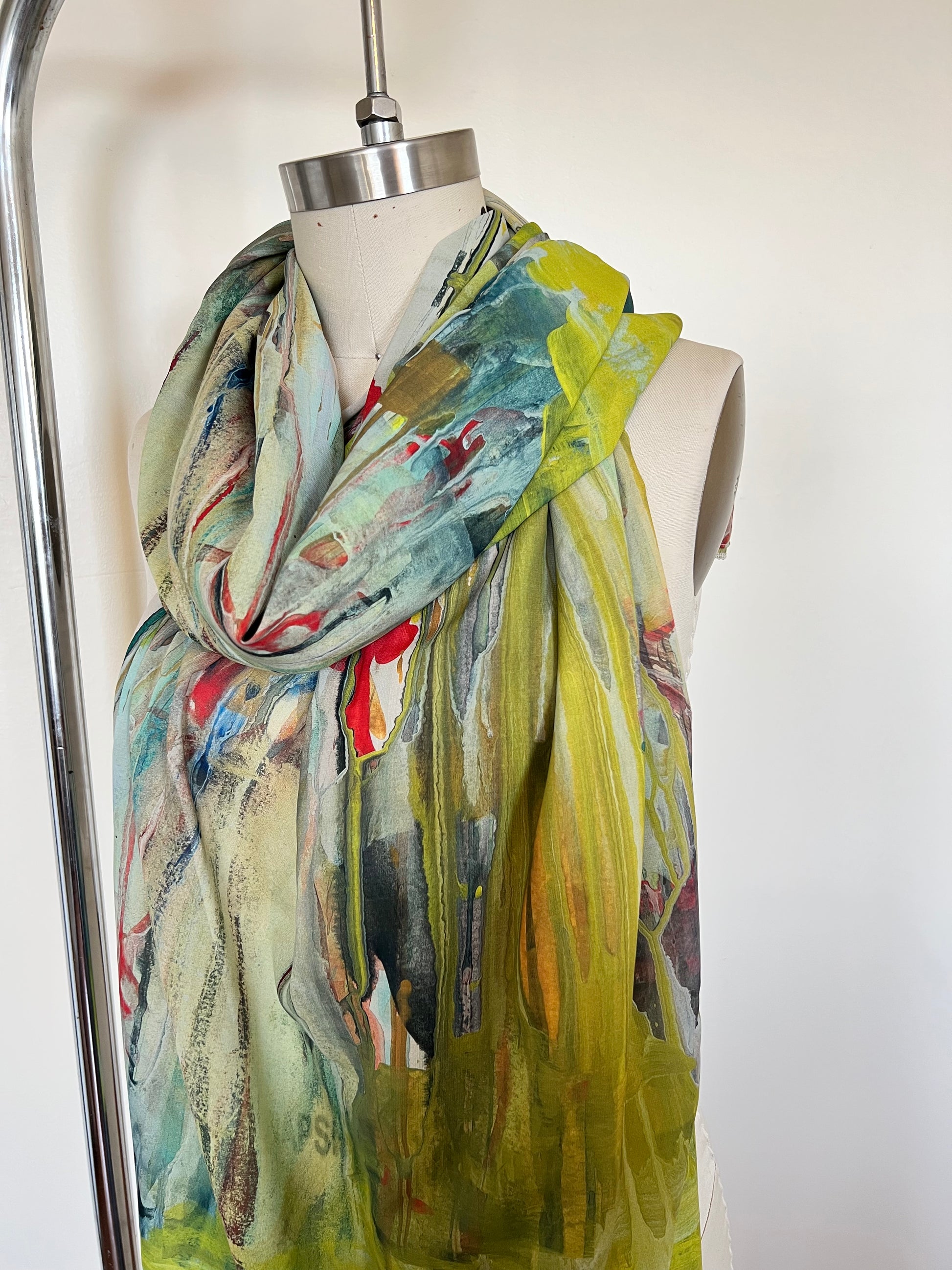 A large chiffon silk scarf with a vibrant, abstract multicolored print, displayed on a mannequin.