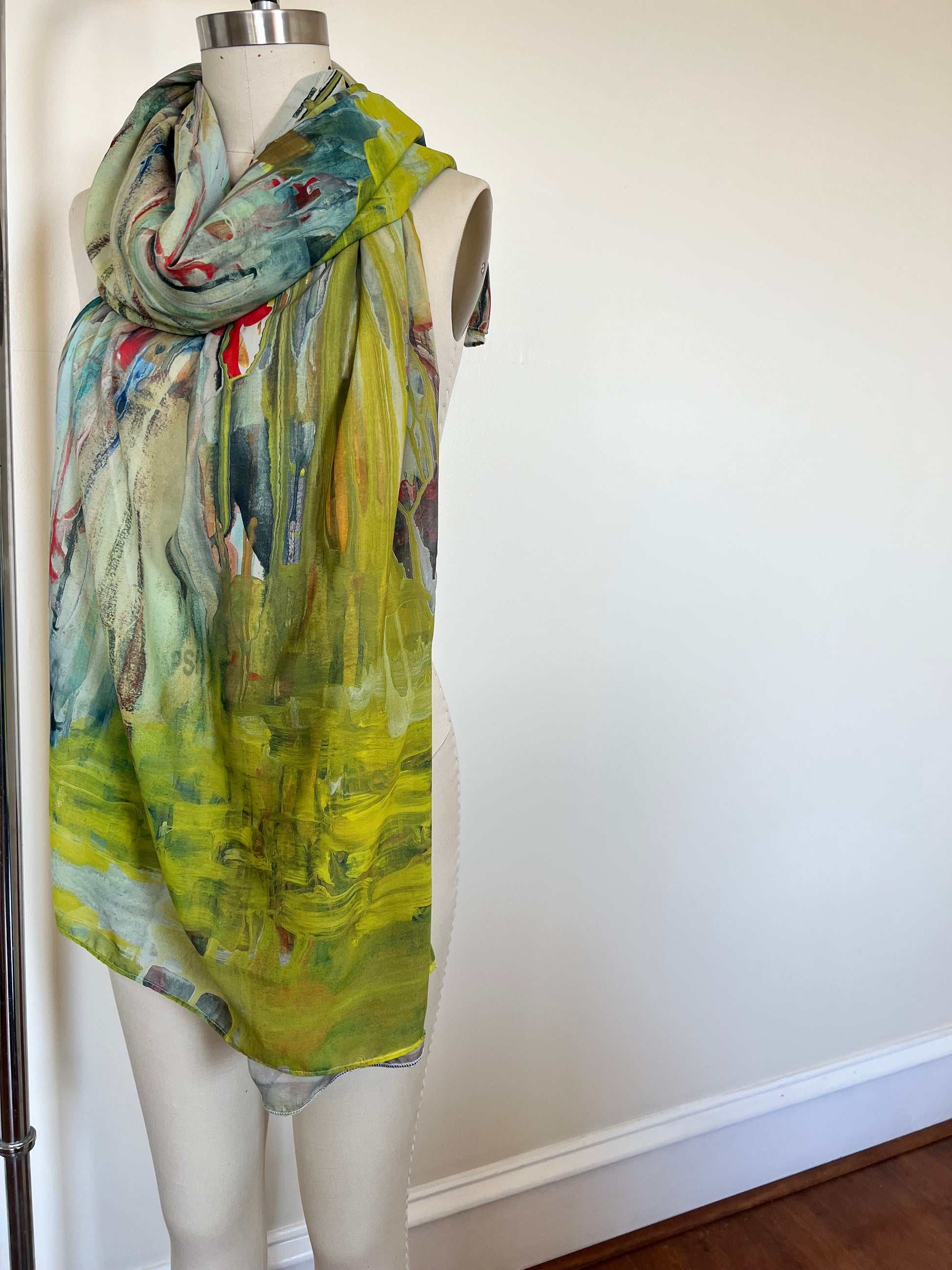 A large chiffon silk scarf with a vibrant, abstract multicolored print, displayed on a mannequin.