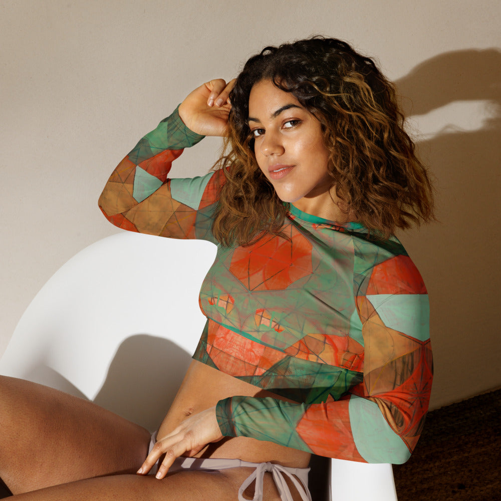 Woman wearing a patterned long-sleeve top and beige shorts against a neutral background