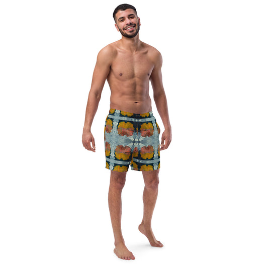 A man standing and facing forward, wearing multicolored swim trunks with a geometric pattern.
