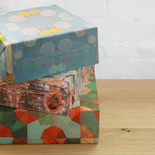 Three stacked sheets of wrapping paper with geometric patterns, displaying a variety of colors including blue, red, and green.