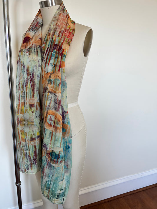 A large chiffon silk scarf with a vibrant, abstract multicolored print, displayed on a mannequin.