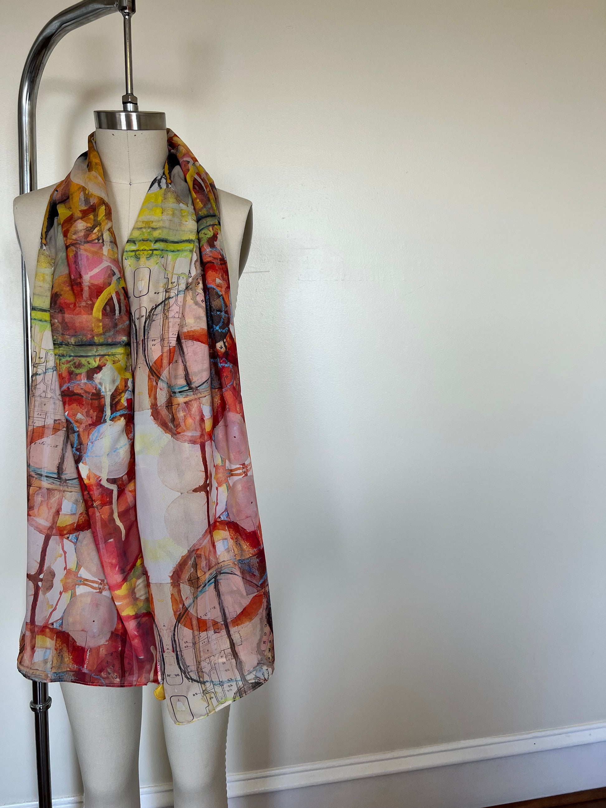 A large chiffon silk scarf with a vibrant, abstract multicolored print, displayed on a mannequin.