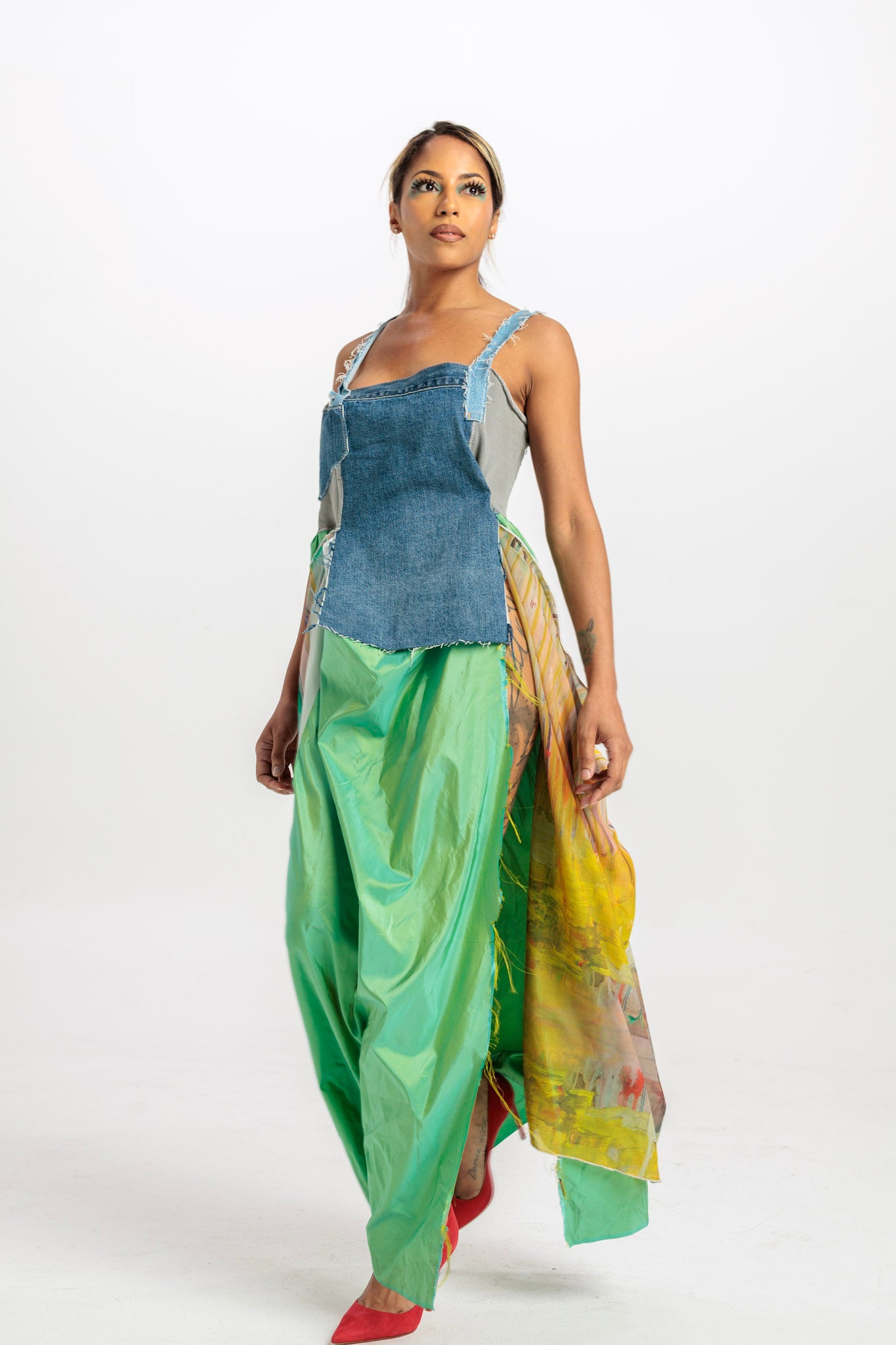 Woman wearing a colorful outfit with a denim top and green pants on a white background